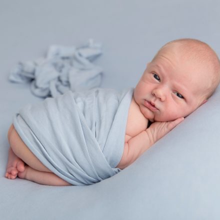 Little Newborn George on a blue background, photoshoot