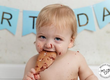 Funny cake smash photo little boy eating a spoon covered in chocolate cake in our studio Leeds