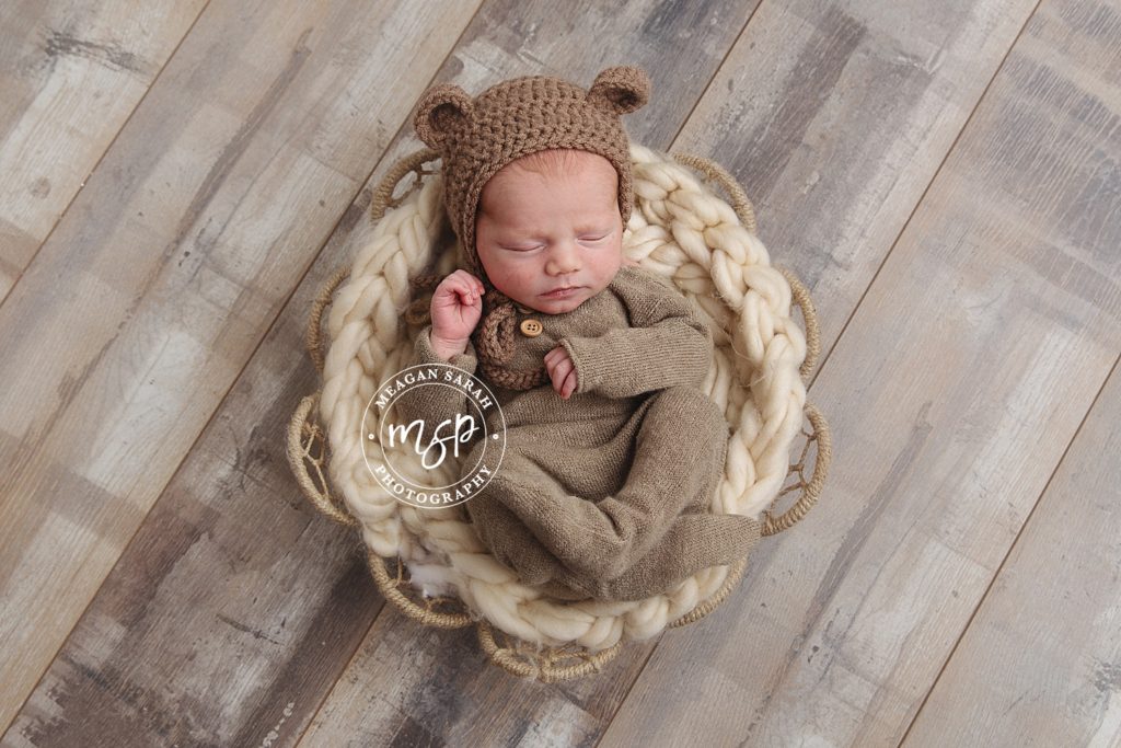 newborn baby in basket with bear ears.