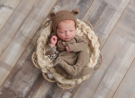 newborn baby in basket with bear ears.