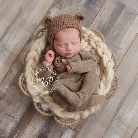 newborn baby in basket with bear ears.