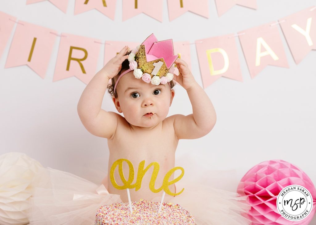 Funny cute baby girl during cake smash photo Leeds, crown, bunting,