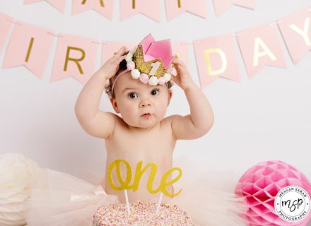 Funny cute baby girl during cake smash photo Leeds, crown, bunting,