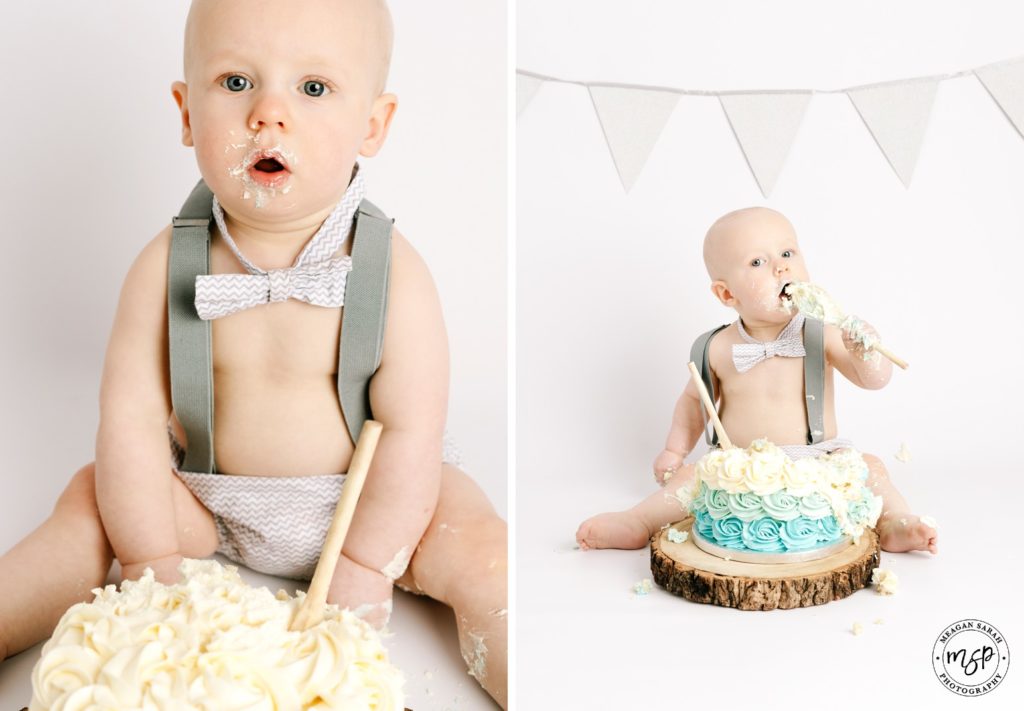 A photo of a baby in grey bow tie and nappy cover. Smashing a cake for his Cake Smash session in Leeds at Meagan Sarah Photography Studio. White background. Grey bunting. 