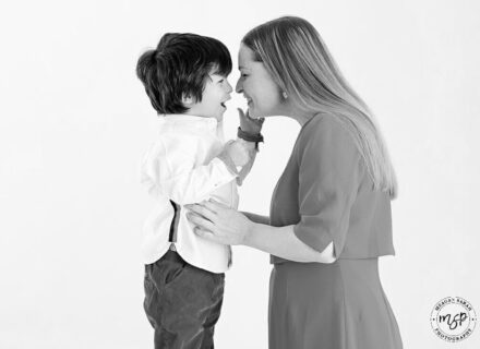 mother and son in white studio background holding mums faces and sons waist