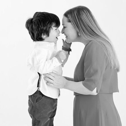 mother and son in white studio background holding mums faces and sons waist