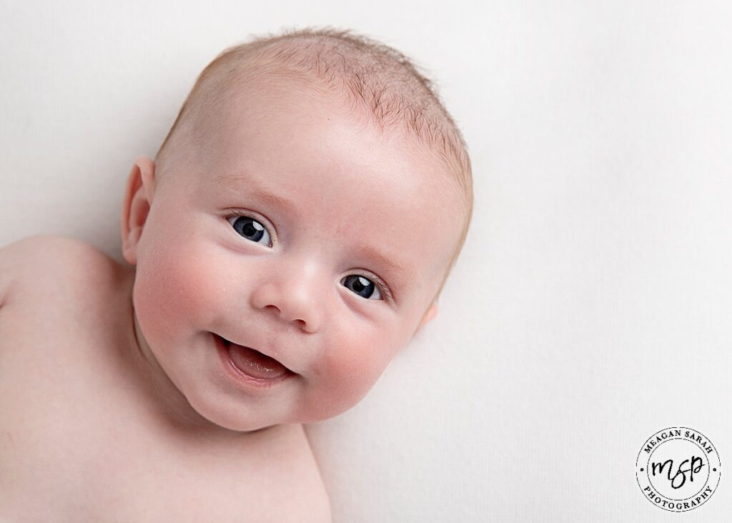 baby boy on white background smiling at the camera