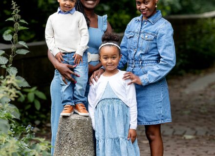family outside, mum and aunt with little boy and little girl all dressed in matching denim in a backdrop of trees all smiling at the camera