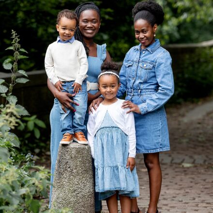family outside, mum and aunt with little boy and little girl all dressed in matching denim in a backdrop of trees all smiling at the camera