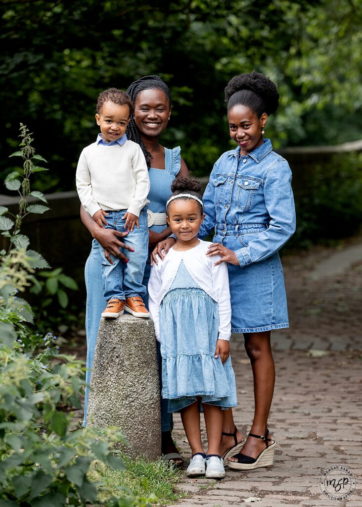 family outside, mum and aunt with little boy and little girl all dressed in matching denim in a backdrop of trees all smiling at the camera