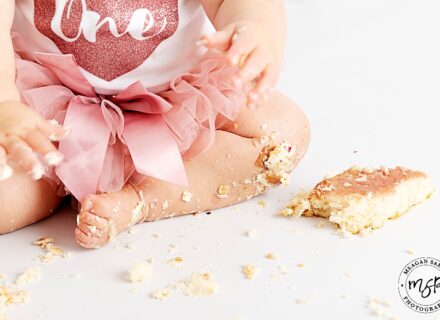 little girls leg. dressed in pink tutu with cake smashed around her