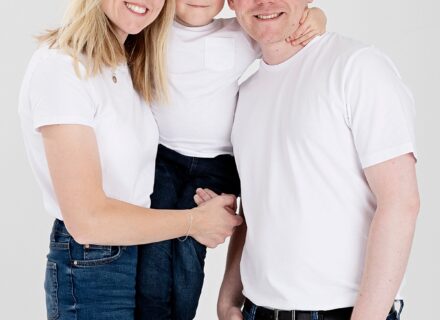 mum and her son and her brother all in white t-shirts and blue jeans smiling at the camera on a white background