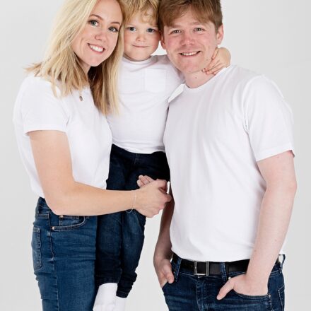 mum and her son and her brother all in white t-shirts and blue jeans smiling at the camera on a white background