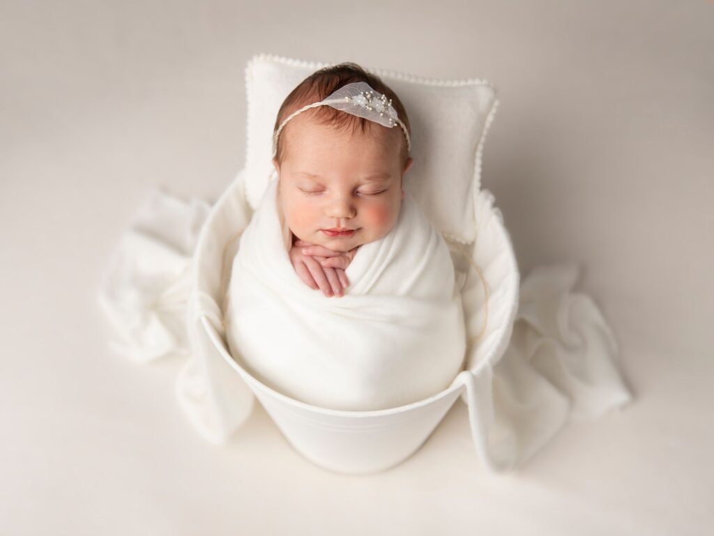 Photo of a newborn baby in a white bucket. Newborn photographer Leeds.
