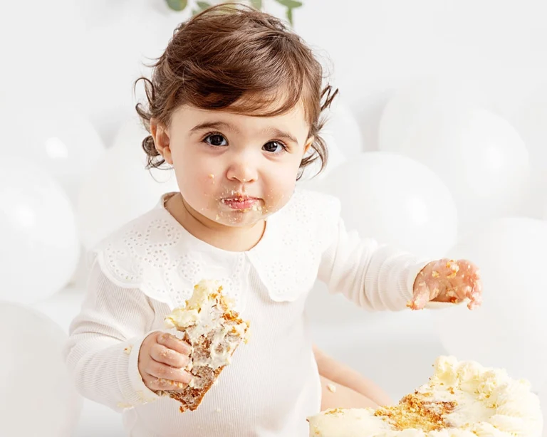 baby girl eating cake at her cake smash photoshoot. Leeds.
