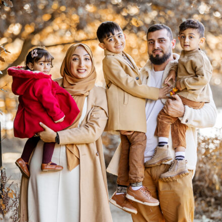 a photo of a family all in warm beige colours to match the autumn leaves background