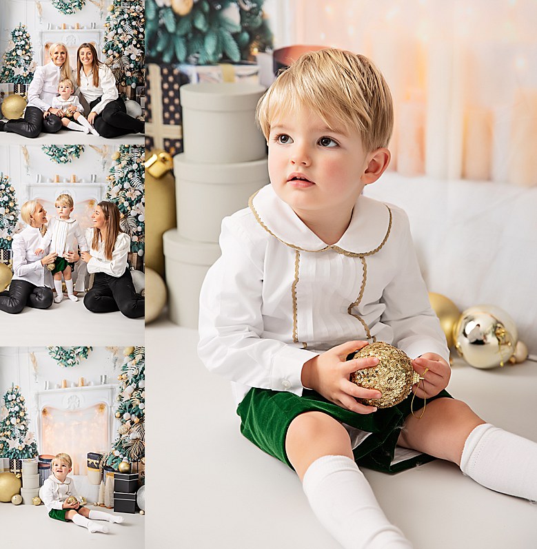 Angelic little blonde boy. Wearing white shirt with gold accents and green velvet shorts. Sitting on a faux christmas set in a photography studio.