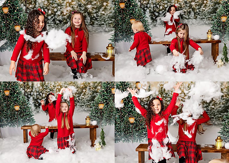 Little sisters having fun throwing faux white snow around photography studio. Playing on a faux christmas studio set. Having fun. Christmas annual photos. Wearing all red.
