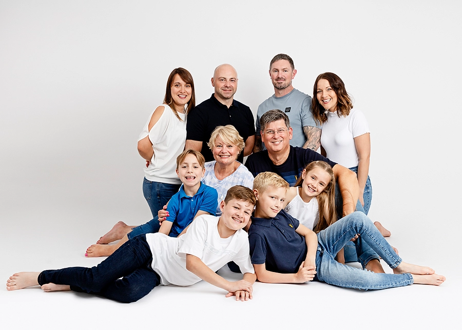 Large family group photoshoot in a white studio. white background. Family of 10. Posing ideas. Leeds photography. Leeds studio photos. Leeds family photographer. Blue and white outfits. Parents, grandparents and children, grandchildren. Things to do in Leeds. Sitting on the floor. Casual relaxed posing. Smiles. Happy. Fun. Meagan Sarah Photography studio Horsforth.