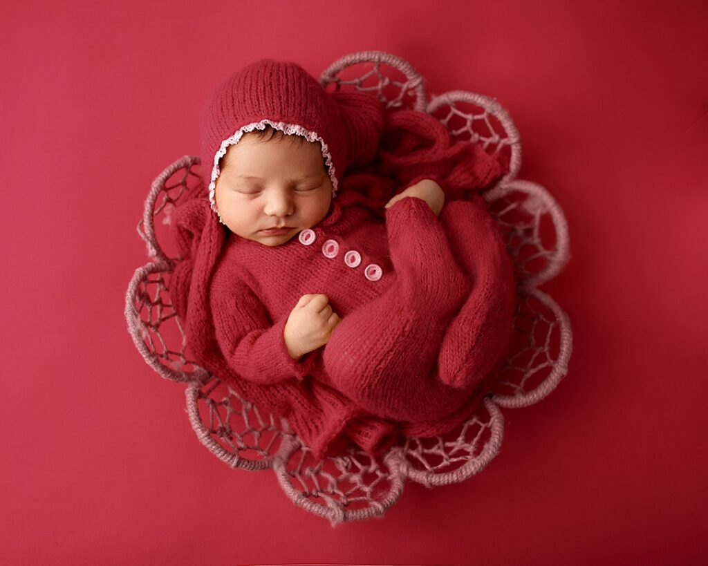 Professional baby photographer Leeds. Pink image of newborn baby laying asleep in basket.