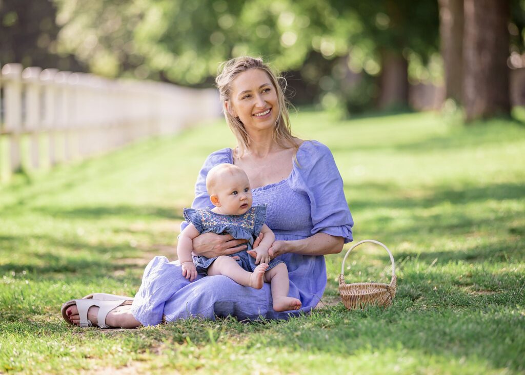 Part of our motherhood mummy and me photo sessions in the park. this is an image of a mother with her baby girl sitting on the short grass with her baby on her knee. both wearing beautiful blue dresses. Image taken at Kirstall abbey, Leeds. Outdoor photoshoots. family portraits. 